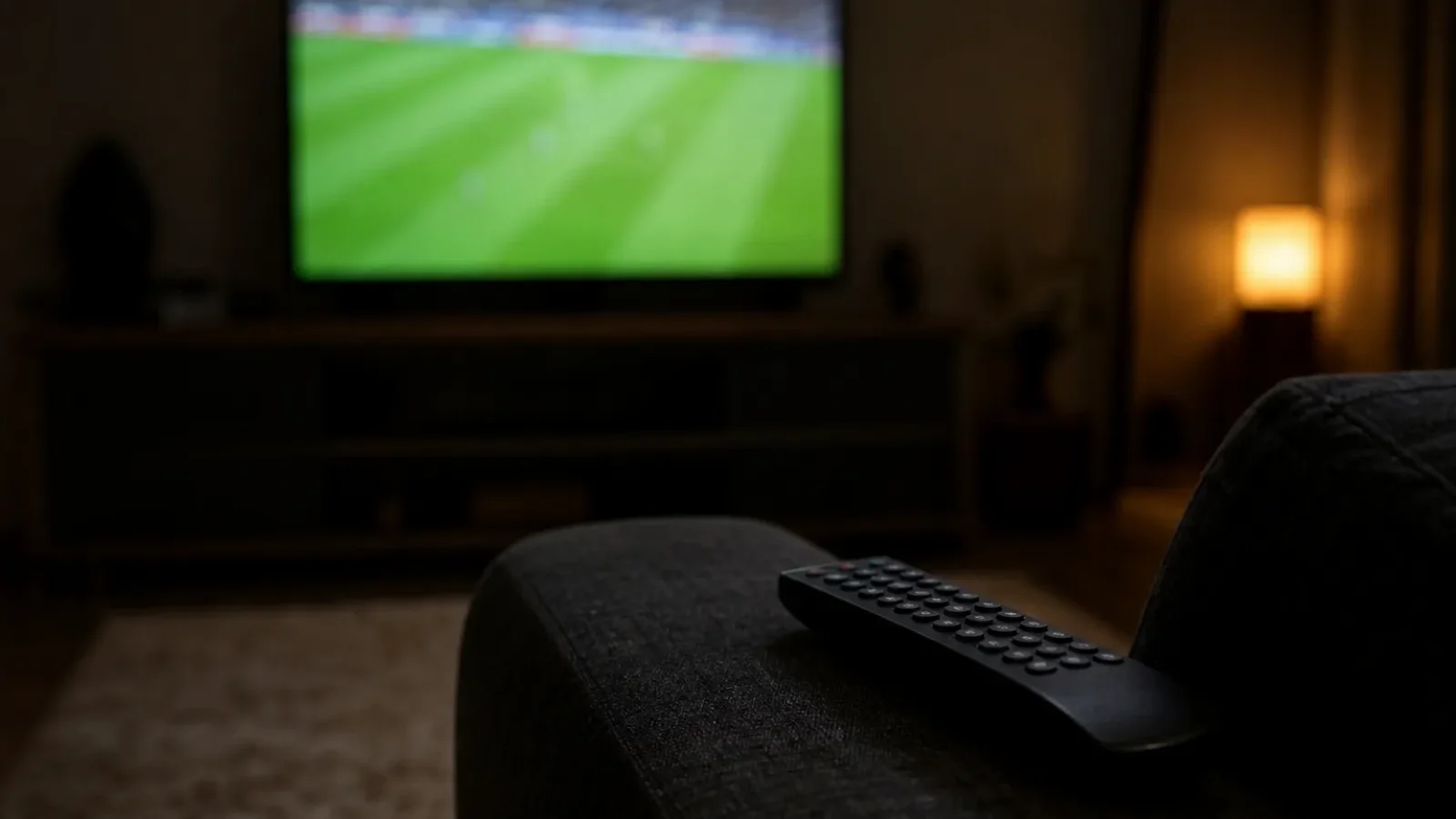 Fernseher mit Fußballübertragung im dunklen Wohnzimmer